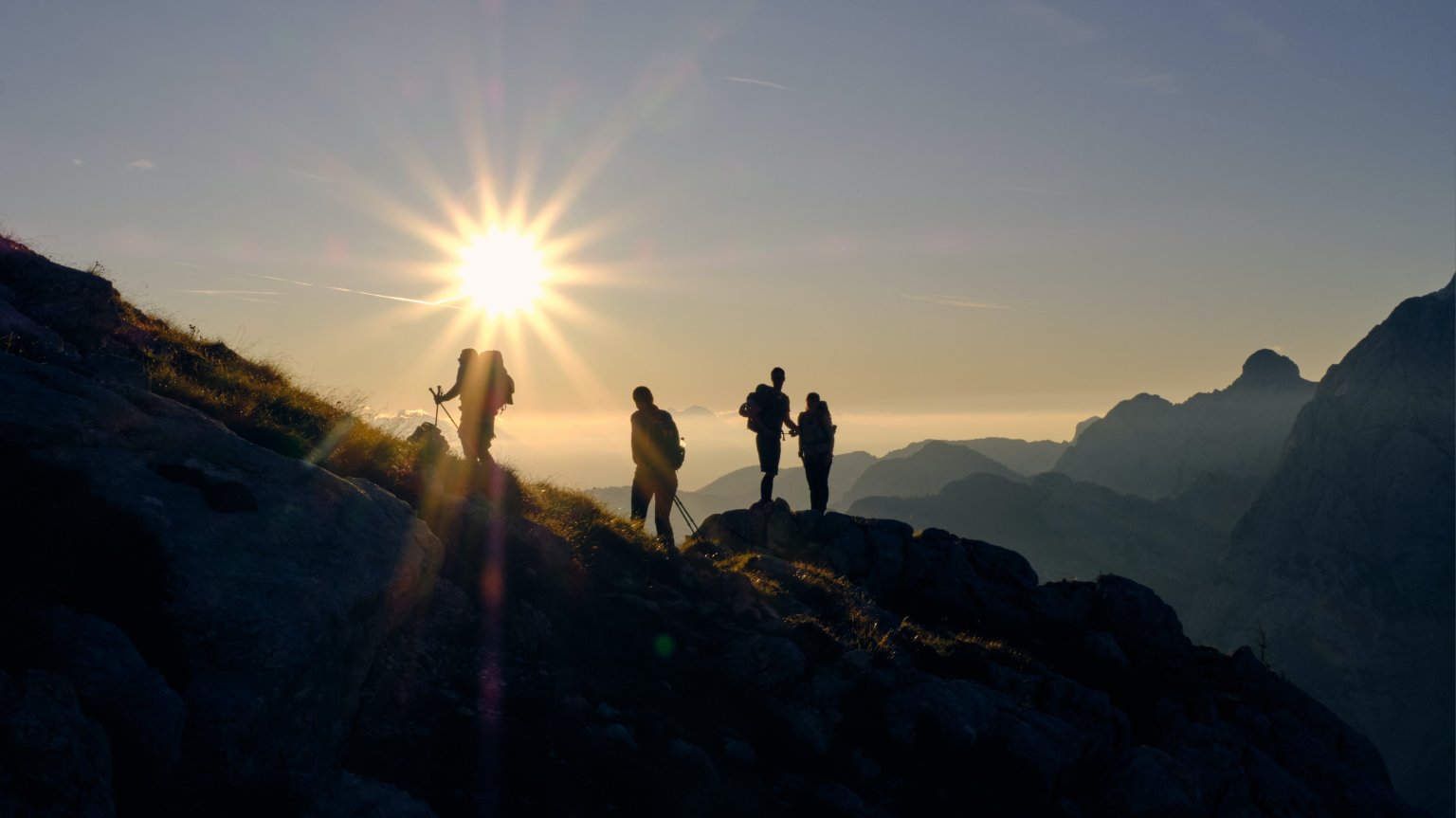 Personen am Wandern im Sonnenuntergang. Kristjan Kotar Unsplash.